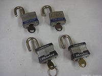 Four used Master brand padlocks, two with blue labels and two commercial with black labels, all open with keys inserted and placed on a white background.