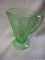 Side view of green glass jug showing floral etched pattern and shaped handle