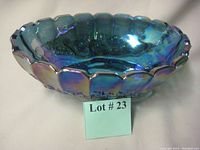 Blue carnival glass footed bowl showing scalloped edge, grapevine embossing, and iridescent finish with blue and purple hues