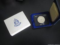 White box with Canada crest logo, showing blue display case inside containing coin.