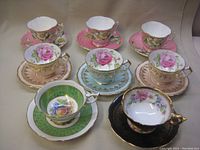 Overview of eight assorted cup and saucer pairs in various floral patterns and colors