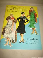 Front cover of paper dolls book showing vintage 1920s fashion illustrations and title.