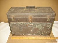 Closed view of the older Kennedy 7-drawer machinist tool box showing metal body with rust and wear, top handle, and front locking latches.