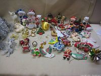 Photo showing a variety of Christmas-themed ornaments laid out on a flat surface including figurines, miniatures, and garland.