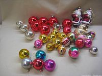 Top-down photo showing assortment of colorful vintage mercury glass ball ornaments including red, gold, pink, multi-colored, silver, and 2 plastic Santa Claus ornaments.
