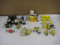 Overview of 20 assorted electrical plugs and adapters including male and female types in white, yellow, black, and orange colors, some panel mounted