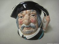 Front detail showing the head of Sancho Panza with a black hat and facial features.