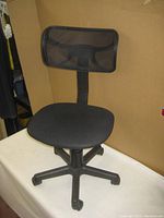 Full side view of black office chair showing mesh backrest and padded seat on five-star rolling base.