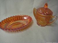 Covered sugar bowl in matching amber carnival glass with handles and finial lid