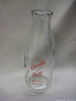 Clear glass milk bottle with red Christies Dairy logo and slogan, no chips or cracks.
