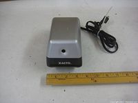 Front view of the silver and black X-ACTO electric pencil sharpener next to a ruler showing size approximately 3 inches wide