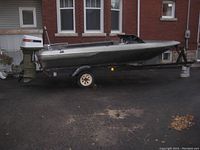 Side profile of entire boat on trailer showing hull condition and outboard motor