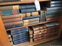Shelf full of antique books with worn covers, showing variety in sizes and binding types.