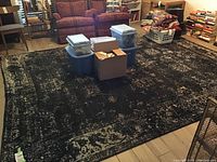 Top view of the large area rug with black and beige distressed pattern and some storage bins on top.