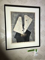 Frontal view of framed abstract art print showing white mat and black wood frame