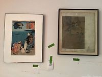 Overview of two framed Asian art prints on a wall, one with bright colors and one faded, both framed.