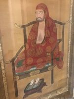 Close-up of painted figure showing seated monk in red robes with gold circular patterns