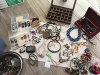 Overall view of clear organizer, wooden box, red jewelry box, trinket box, assorted necklaces and beaded items on table