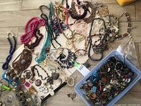 Overview of necklaces, bracelets, earrings, rings and plastic bin with assorted pieces