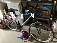 Roadmaster black and blue mountain bike with front suspension and knobby tires, two bike helmets placed near rear wheel; one is pink and the other purple