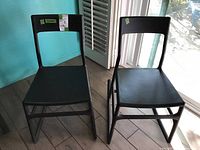 Two black plastic rocking chairs side by side showing full front and rocking base profile.