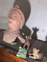 Photo showing the large terracotta bust of a human figure alongside two smaller animal clay statues.