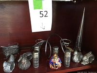 Metal and colorful elephant salt and pepper shakers, animal zodiac napkin holders, small metallic decor items on a shelf