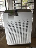 Front view of white Winix air purifier with perforated front panel and control buttons on top, 21 inch height indicated.