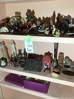 Shelves showing a collection of small world travel souvenir and art decor pieces including animal figurines, decorative plaques, and various small sculptures in mixed materials.