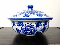 Side view of antique ceramic pot with blue floral decoration and lid with knob handle