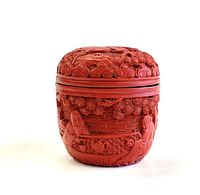 Front view of the red cinnabar carved trinket box showing intricate floral and figure carvings