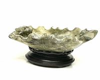 Side profile of the multicolor carved jade brush washer on a wooden stand, showing ruffled edges and natural color variations.