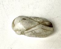 Top side view of the white jade cicada pendant showing the smooth polished surface and carved wing details.