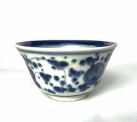 Front side of the antique Dao Guang blue and white tea cup showing floral pattern and flared rim.