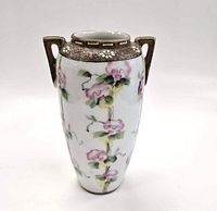 Front angled view of the white vase with pink floral designs and brown handles on a white background.