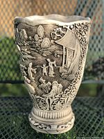 Front view of the ceramic vase showing detailed carvings of figures near a pagoda and landscape.