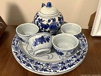 Front view of the blue and white porcelain tea set including teapot, four cups, and tray.