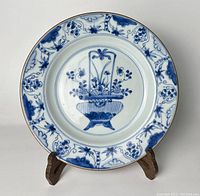 Front view of the blue and white porcelain plate showing the flower basket motif and border design.