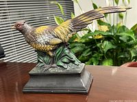 Side angled view of plaster pheasant bird display ornament showing detailed painted feathers and standing posture on base.
