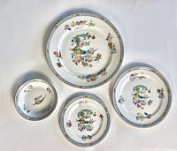 Four ceramic plates with exotic bird and floral designs, arranged on white background to show front decoration and sizes.