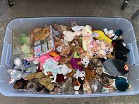 Top down view of large plastic bin filled with assorted Beanie Babies plush toys of various animals and colors with Ty tags.