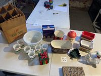 Overview of all items including egg nog set, baking pans, decorative boxes, plush, and light-up sign displayed on table.