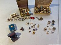 Wide view showing assortment of clip-on earrings, rings, cufflinks, and tie-tacks, some inside display boxes.