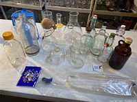 Overview of all assorted Pyrex lab glassware and vintage bottles arranged on a table.