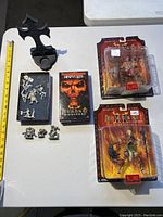 Lot overview displaying Diablo action figures, D&D miniatures in a box, Diablo collectible boxes, and gothic votive holder next to a ruler for size reference.