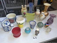 Full view of 17 assorted decorative vases and pots of various styles and colors displayed on a table