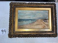 Full view of vintage beach scene painting in carved ornate gold wooden frame showing scratches and wear on frame and canvas.