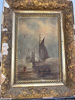 Front view of the small framed painting showing sailboats on water in an ornate gold frame with visible wear.