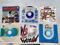 Top view of six 45 RPM vinyl records in sleeves, featuring The Monkees and The Archies.