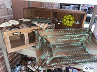 Wooden crate with label holders, decorative apple tree with green apples, wooden and glass hinged box, three small wooden wall hangings, two rectangular patinated metal trays made in India grouped on a table.